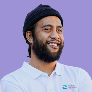 Man wearing beanie and HealthcareNZ shirt on purple background