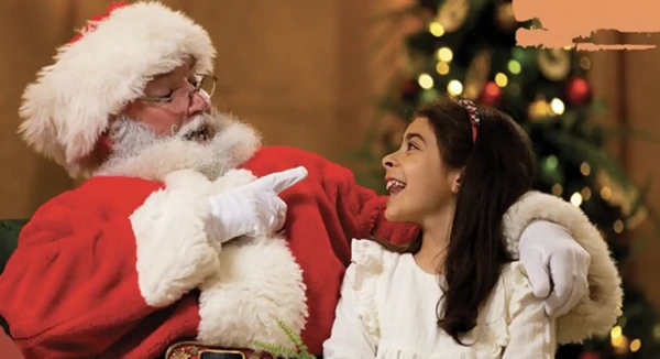 A young girl sitting next to Santa