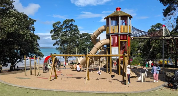 Takapuna park has a swing set, a hamster wheel, a tower with two tunnel slides and a webbed jungle gym. 