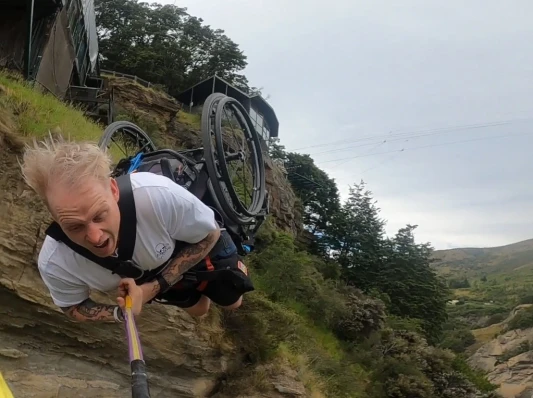 man in wheelchair on bungy rope in canyon