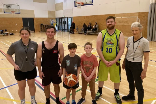 A group of six deaf basketball players and referees standing in a gymnasium.