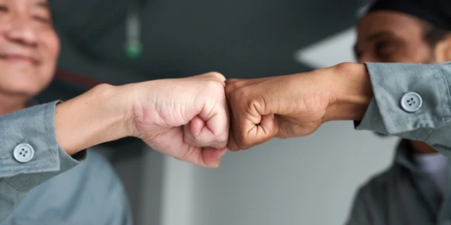 A close up of two men doing a fist bump