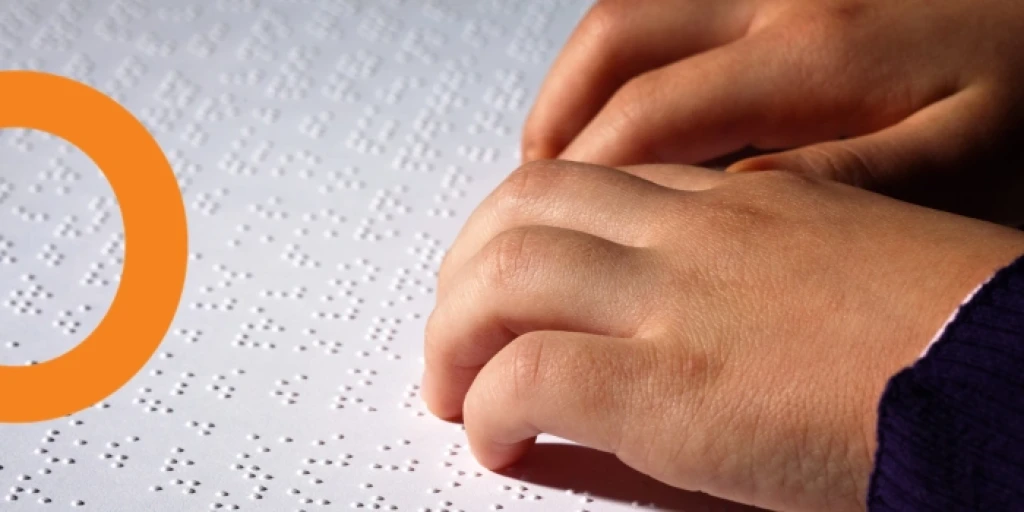 A close up on person's hands running across a page of braille.
