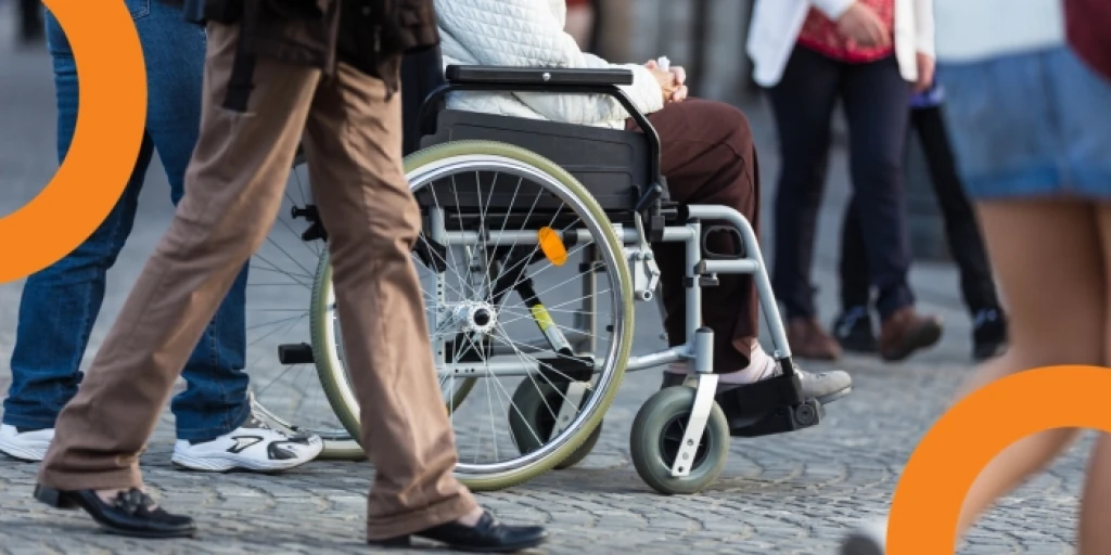 A wheelchair users wheeling through a crowded street. The shot is taken from waist height.