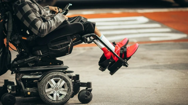 A man using a power wheelchair photographed from the chest down.