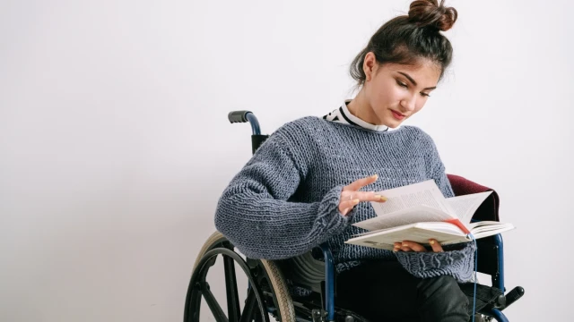 A young woman in a wheelchair reading a book