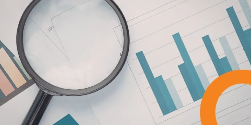 A magnifying glass on top of papers featuring graphs
