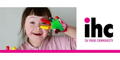 A young Down Syndrome girl with painted hands in front of her face. Ihc in your community appears next to her.