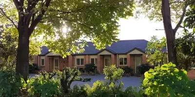 A brick exterior of the northwood lodge punctuated by leafy trees