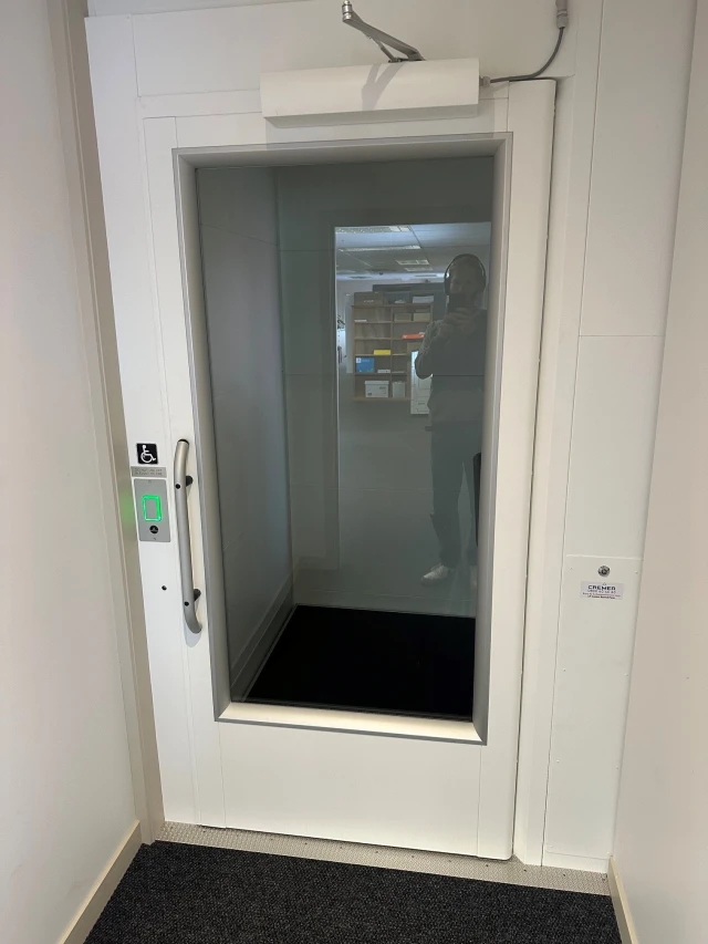 The lift/elevator at Kauri Museum. It is a pull door elevator with a glass front.