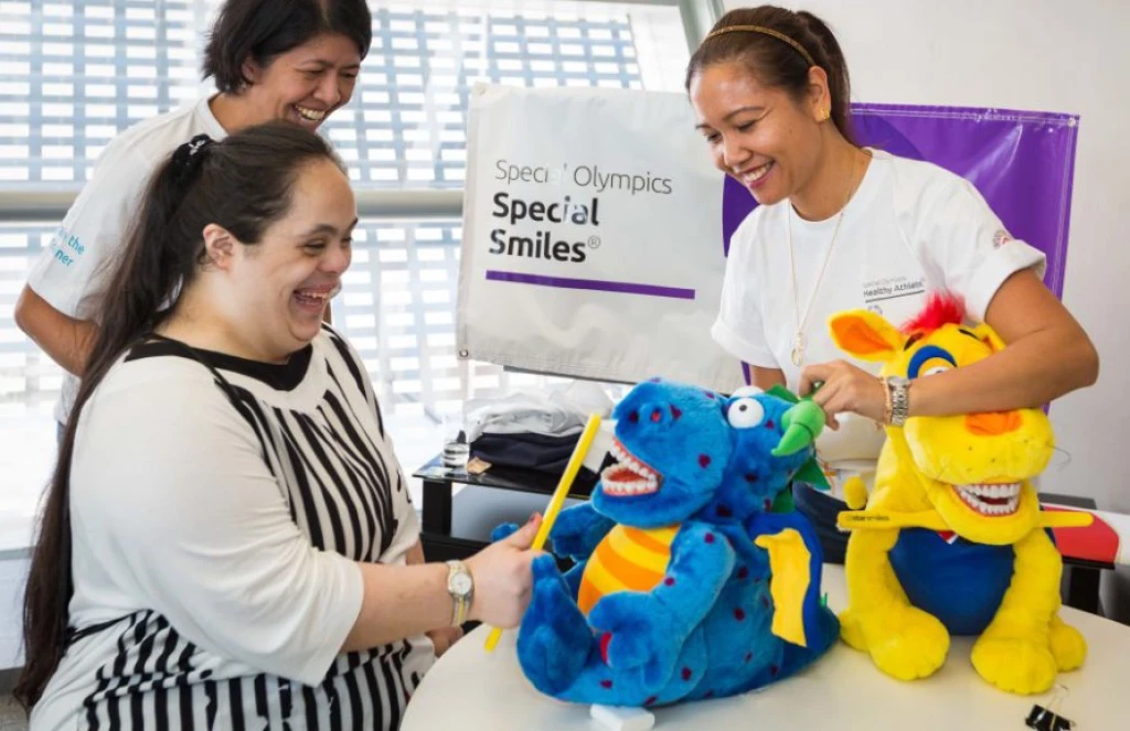 Woman in a black and white striped apron brushing the teeth of a blued dragon soft toy