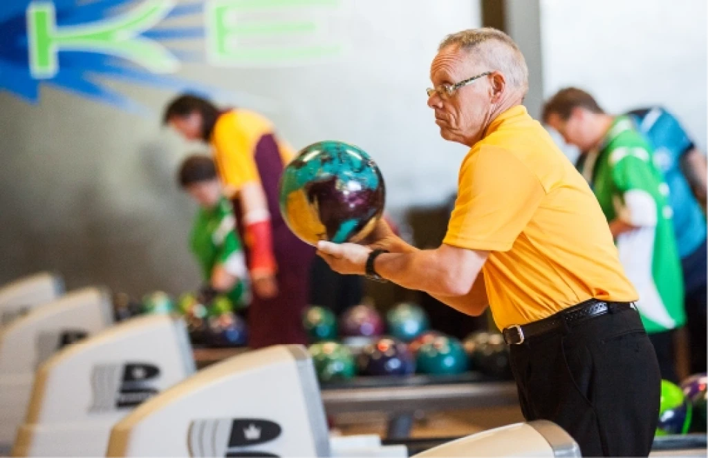 Man in an orange shirt about to bowl a bowling ball