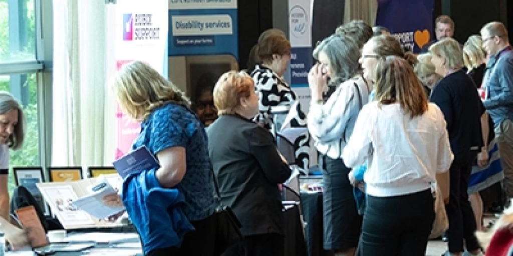 A crowd of people browsing conference stalls