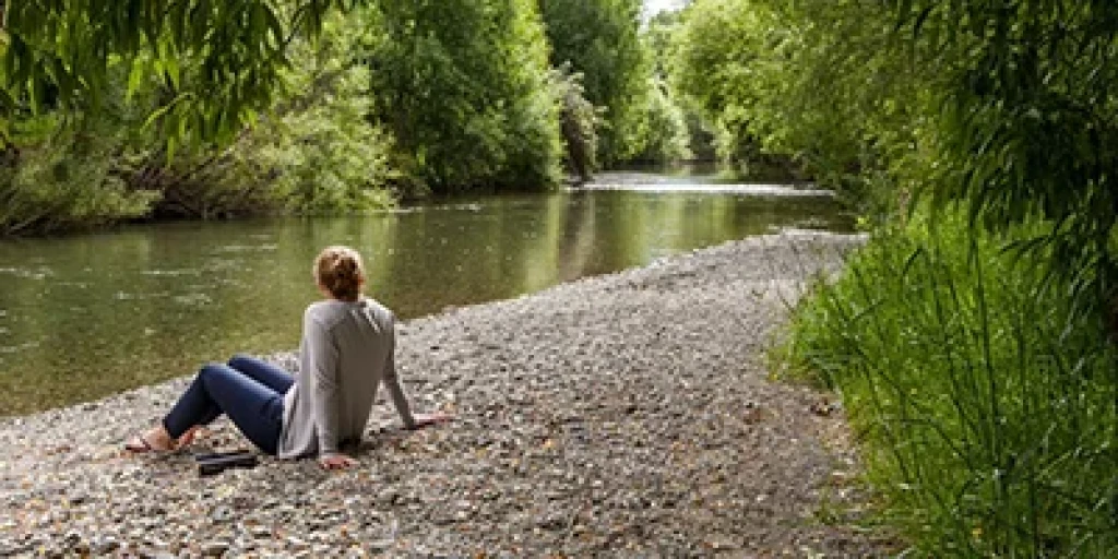 A woman sitting on stones next to a river