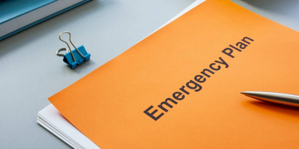 A stack of papers on a desk, with the top one reading 'Emergency Plan'