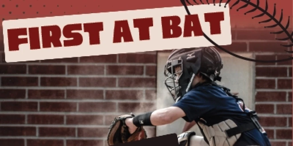 A voy in softball catcher gear with the words 'First at Bat' written across the top