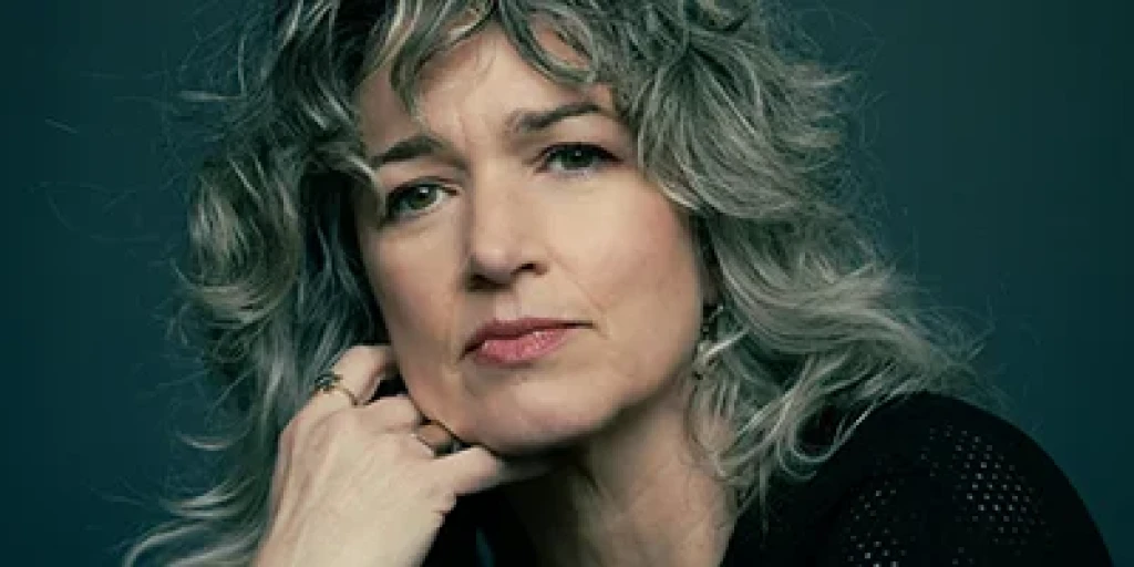 A close up on Julia Deans, who has long curly grey hair and wears a black shirt.
