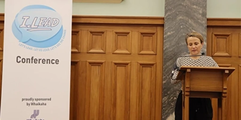 Whaikaha Chief Executive Paul Tesoriero speaking behind a lecturn at the I.Lead conference.