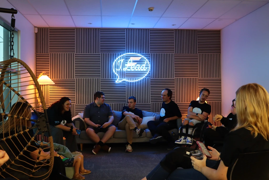 The I. Lead team sitting and socialising in room with dim and neon lighting.