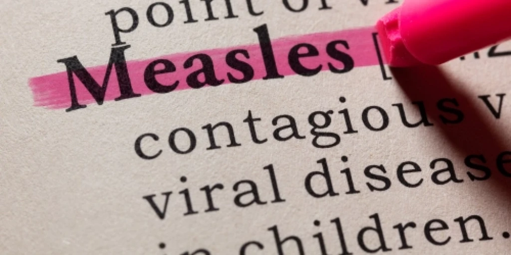 The world measles highlighted in pink in a dictionary