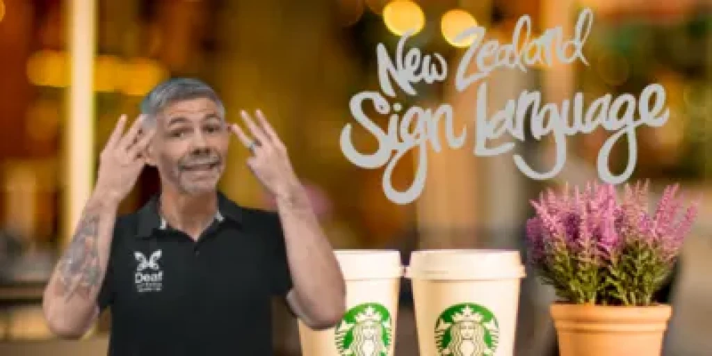 NZSL man signs next to two cups of starbucks coffee
