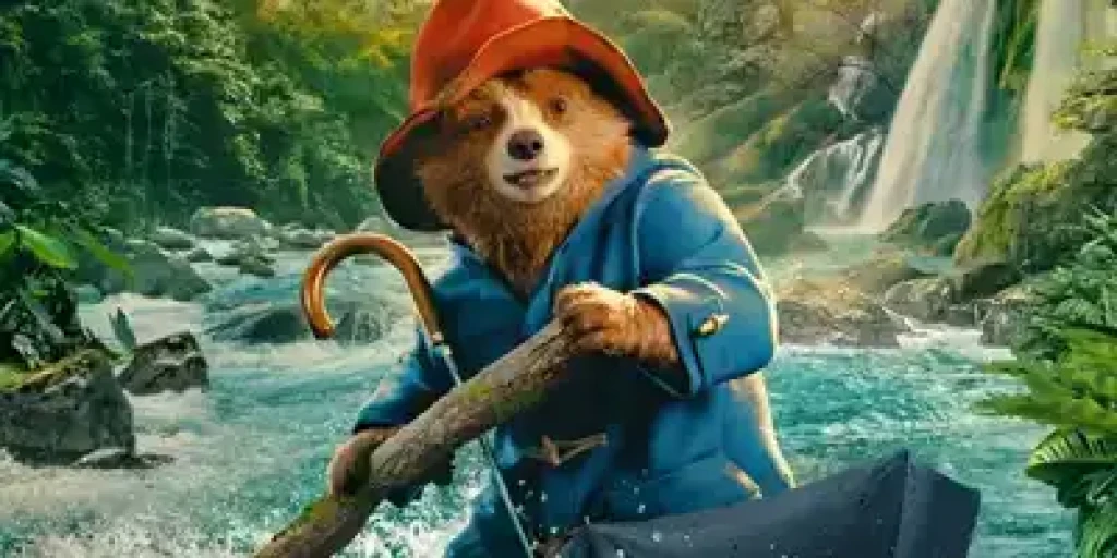 Paddington is a spectacled bear using an umbrella as a boat along a river.