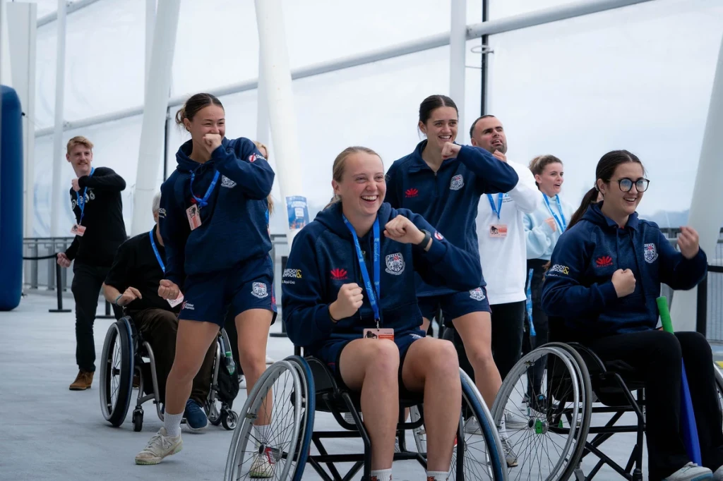 A group of people doing exercises at Power in the Park 2024. Some are in wheelchairs and some are standing.