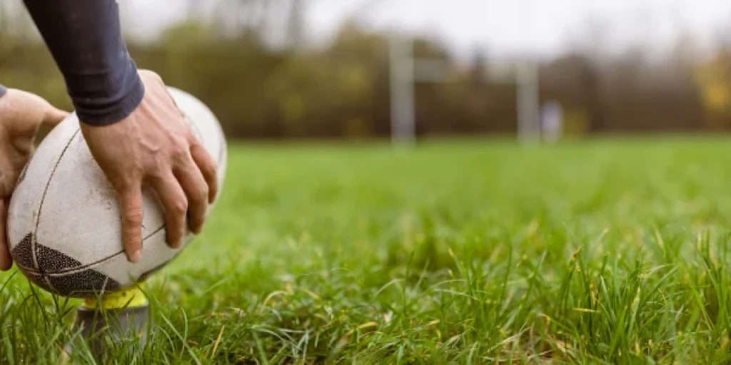 Close up on a rugby player's hands placing a rugby ball on a kicking tee