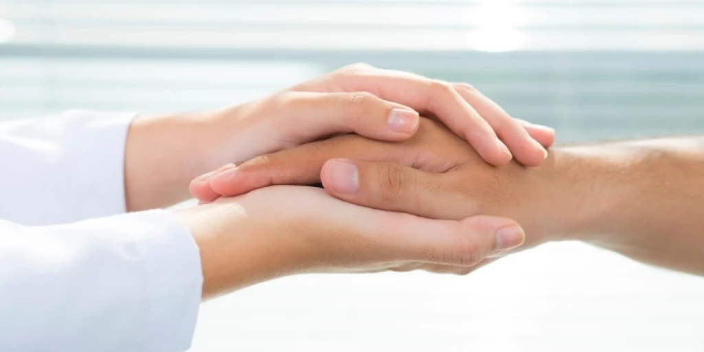 Close up of a person's hands hold onto another person's right hand.