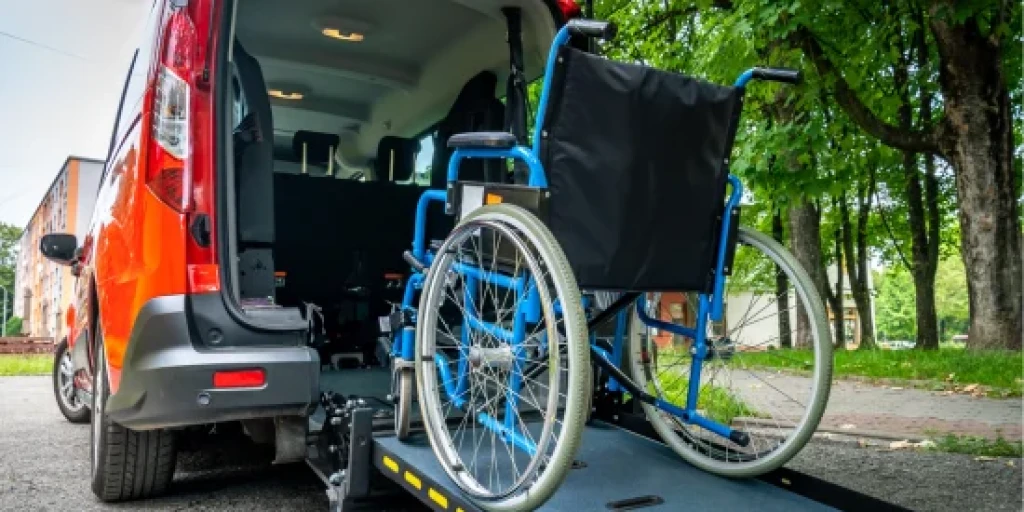 A blue manual wheelchair on a ramp coming out the back of a red van