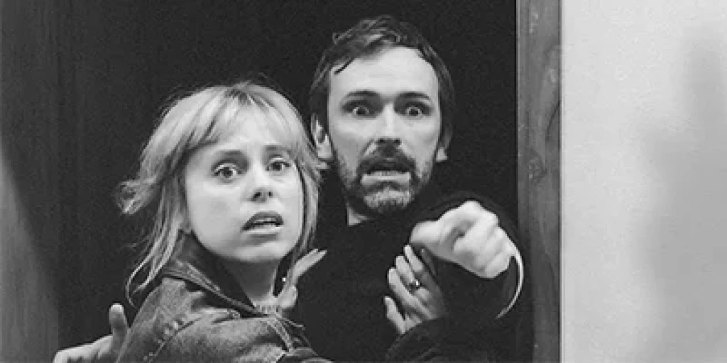 A closeup of a man and women with shocked, scared expressions.