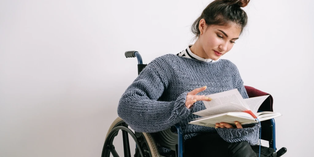 A young woman in a wheelchair reading a book